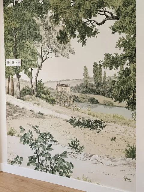Mural de paisaje verde instalado en una pared con rodapié blanco