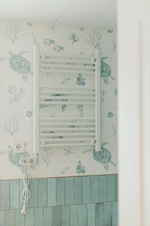 Papel de motivos marinos instalado detrás de un radiador toallero