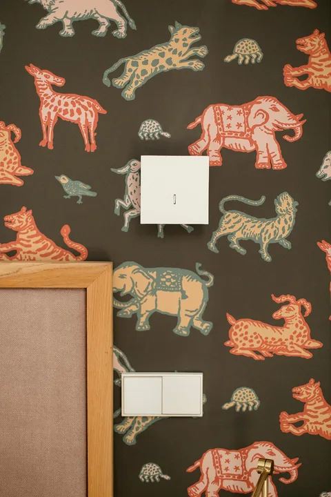 Detalle del papel de animales instalado alrededor de interruptores en un dormitorio