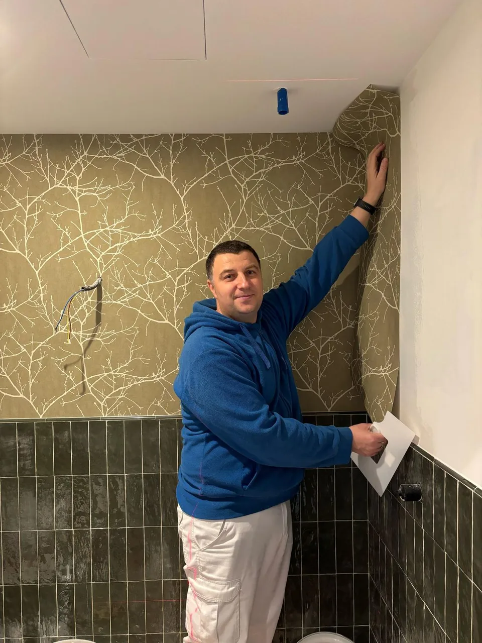 Silviu Floceanu instalando papel pintado de ramas en un baño