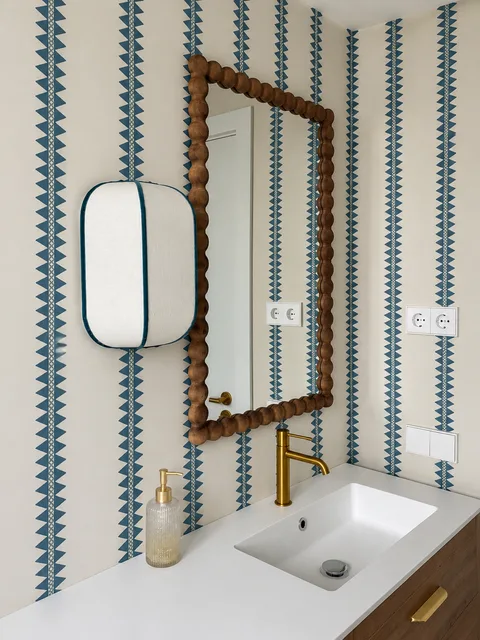Detalle de las franjas de papel azul alrededor del espejo y los mecanismos del baño