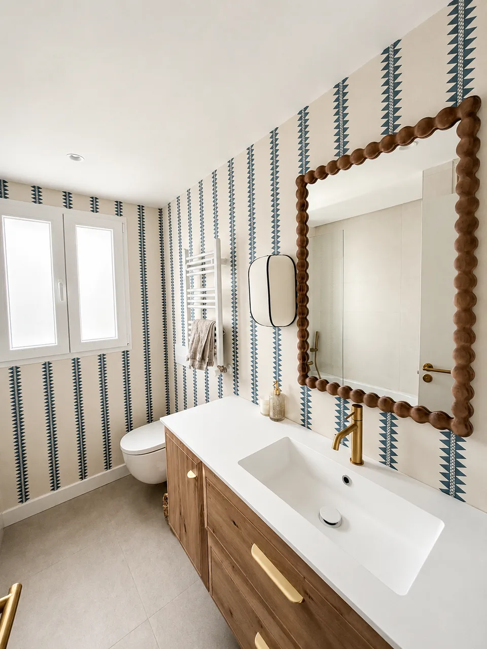 Instalación de papel pintado azul en un baño con espejo de madera y grifería dorada
